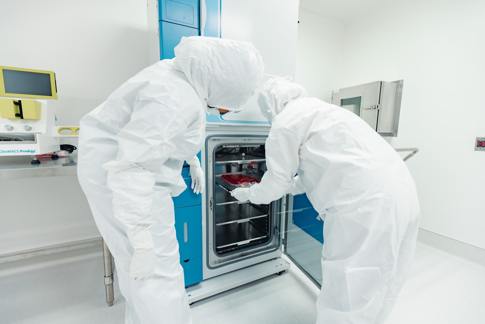 Operators loading an incubator beside a CliniMACS Prodigy